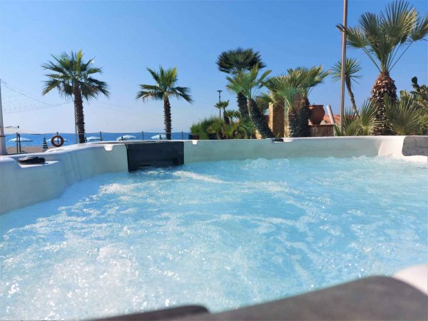 Vasca idromassaggio con palme e vista mare.