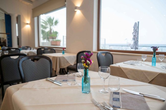 Dettaglio di tavolo apparecchiato in ristorante con vista mare.