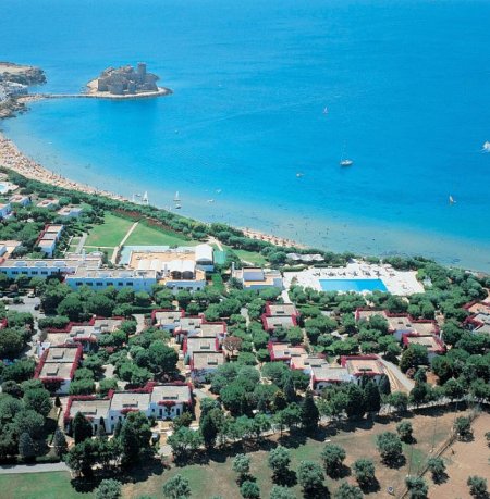 Vista aerea di un villaggio turistico con spiaggia e mare azzurro.