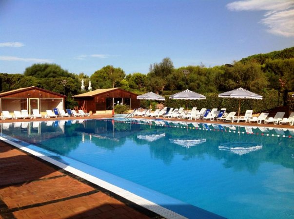 Piscina all'aperto con lettini e ombrelloni.
