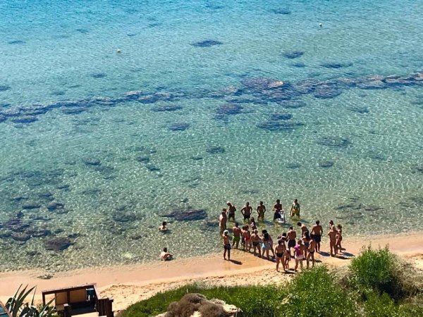 Gruppo di persone sulla riva del mare cristallino.