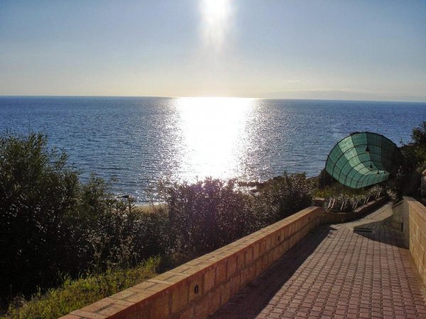 Sentiero lastricato conduce al mare, illuminato dal sole.