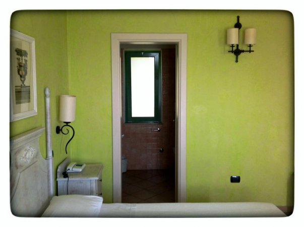 Interno di una camera da letto verde con vista su un bagno con porta socchiusa.