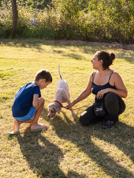 Donna e bambino con cane su prato.