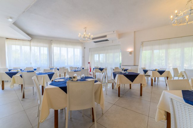 Sala da pranzo con tavoli apparecchiati.