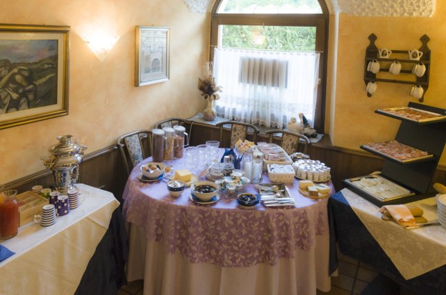 Tavolo rotondo con buffet di colazione in una sala accogliente.
