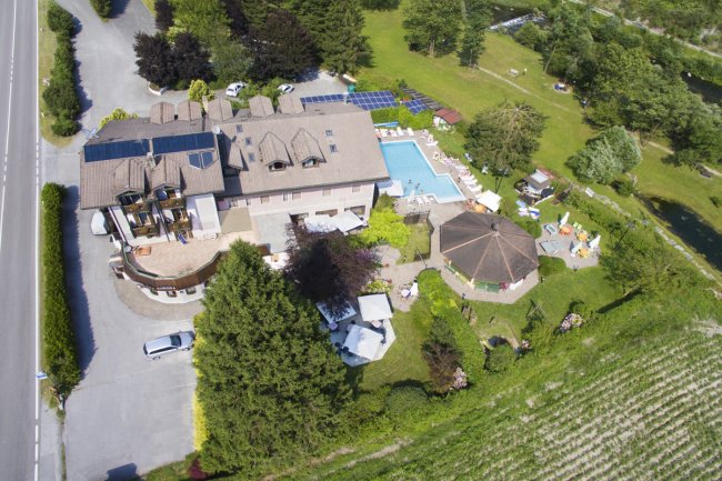 Vista aerea di un edificio con piscina e giardini attorno.