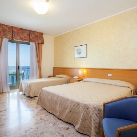 Due letti in una camera d'hotel con vista mare e arredi classici.