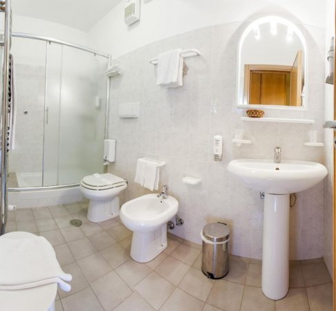Bagno moderno con lavandino, bidet, doccia in vetro e specchio illuminato.