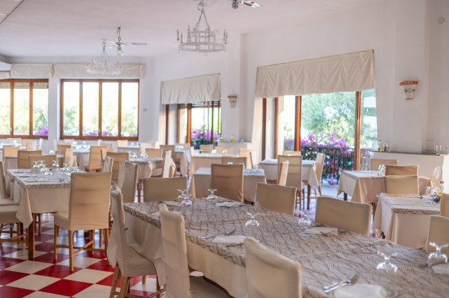 Sala da pranzo con tavoli apparecchiati.