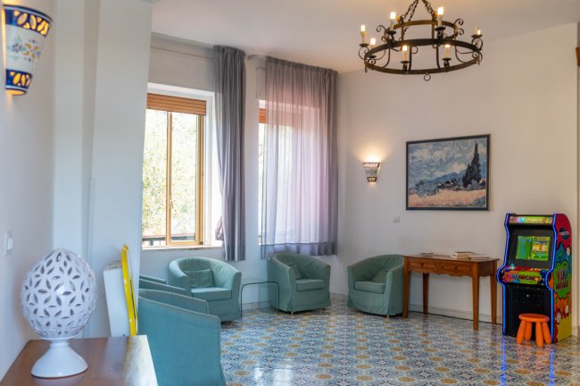 Salotto con poltrone, opera d'arte e macchina arcade.