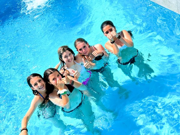Cinque persone sorridenti in piscina.