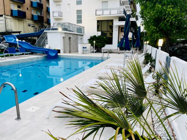 Piscina con scivolo blu e lettini.