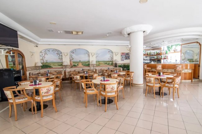 Caffetteria con tavoli rotondi e sedie in legno.