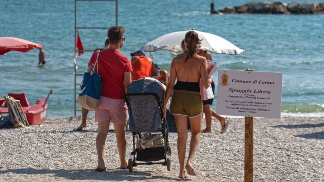 Famiglia cammina su una spiaggia di ciottoli.