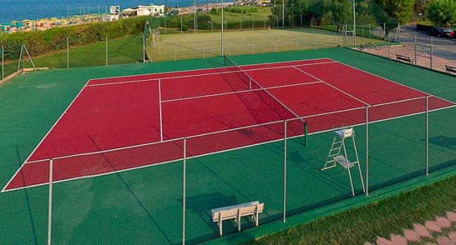 Campo da tennis rosso all'aperto vicino al mare.