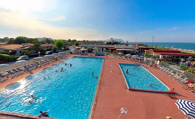 Due piscine all'aperto con lettini e persone che nuotano.