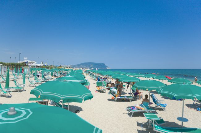 Spiaggia con ombrelloni verdi e mare azzurro.