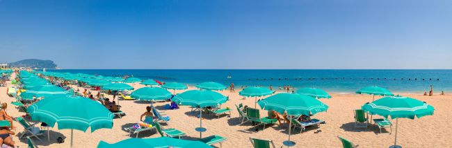 Spiaggia con ombrelloni verdi sotto un cielo terso.
