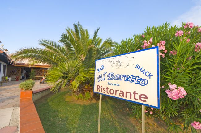 Cartello di un ristorante tra piante e fiori.
