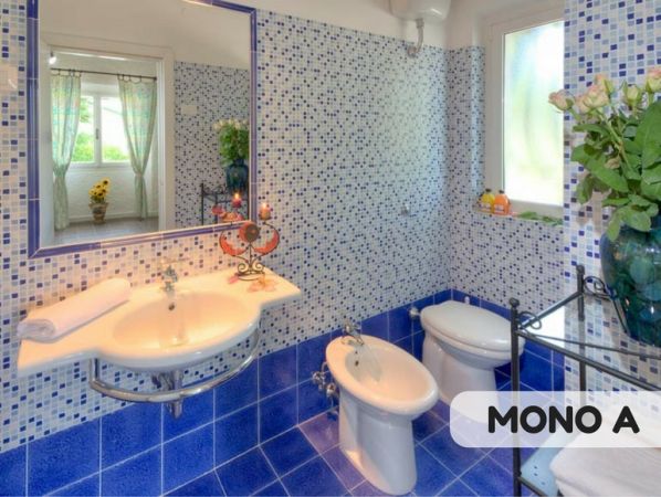 Bagno con piastrelle blu e bianche, bidet e doccia.