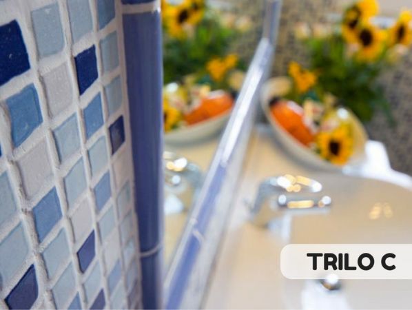 Dettaglio di mosaico blu con lavabo e fiori.