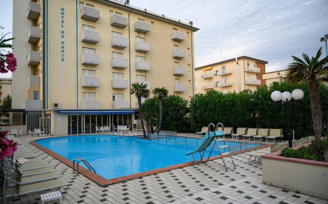 Piscina esterna con scivolo, circondata da lettini.