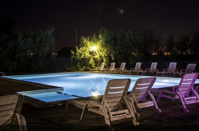 Piscina notturna con sdraio illuminate.