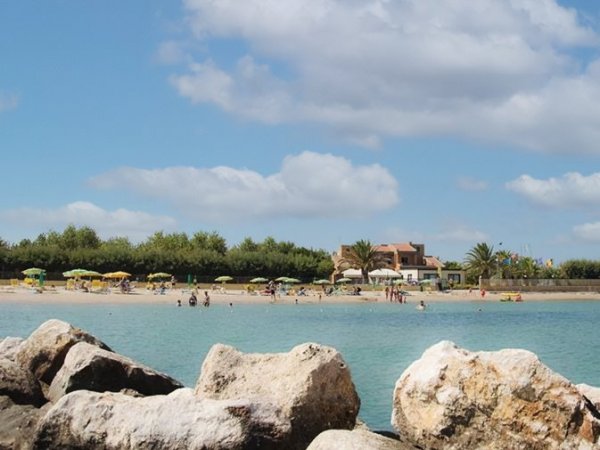 Spiaggia con mare calmo e ombrelloni.