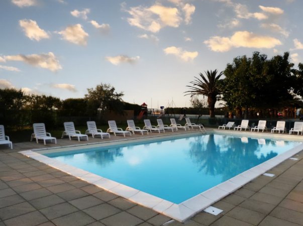 Piscina all'aperto con lettini intorno al bordo.
