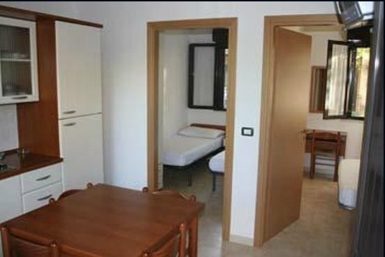 Interno di un appartamento con cucina e porta aperta verso una camera.