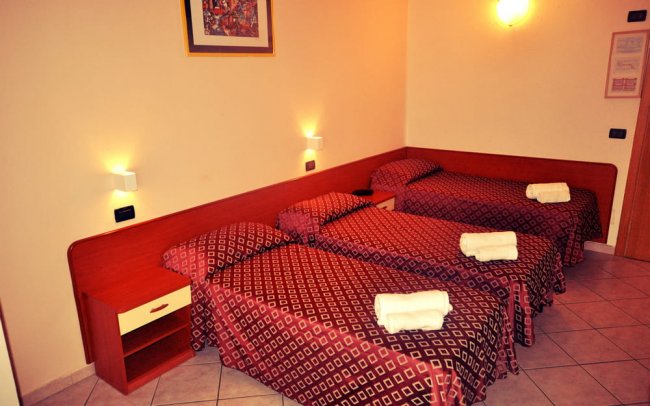 Camera d'albergo con tre letti singoli.
