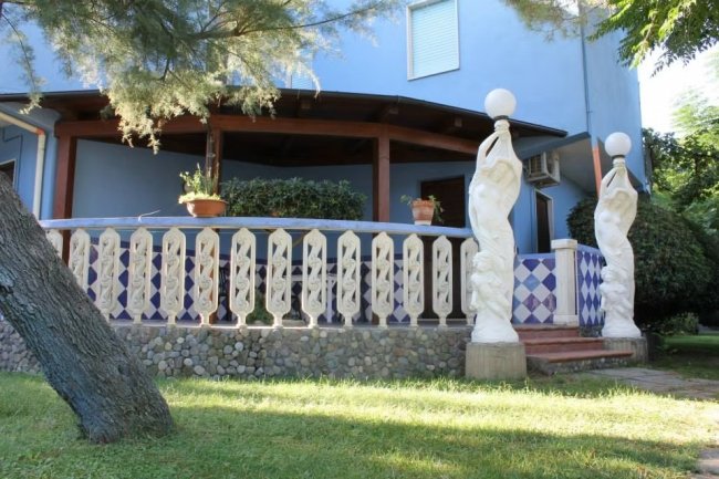 Terrazza blu con statue e piante in vasi.