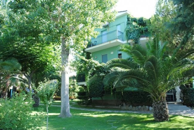 Edificio verde circondato da alberi e piante.