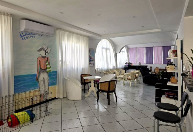 Sala luminosa con arredi moderni, pavimento piastrellato e un murale di una donna sulla spiaggia.