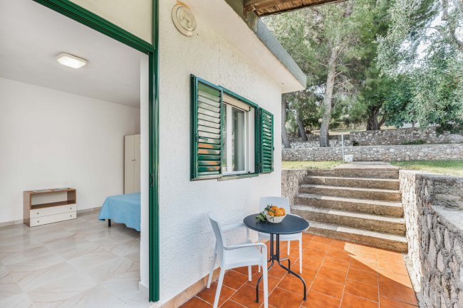 Terrazza esterna con tavolo, sedie e vista sul giardino.