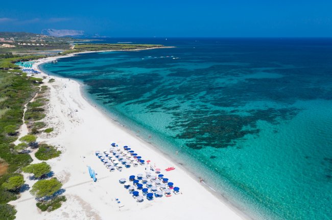 Spiaggia bianca con ombrelloni, mare turchese.